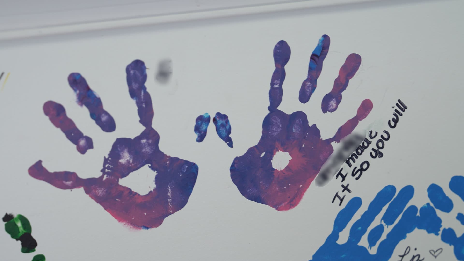 Painted handprints on the wall at Hoffman Academy, each one representing a student's growth